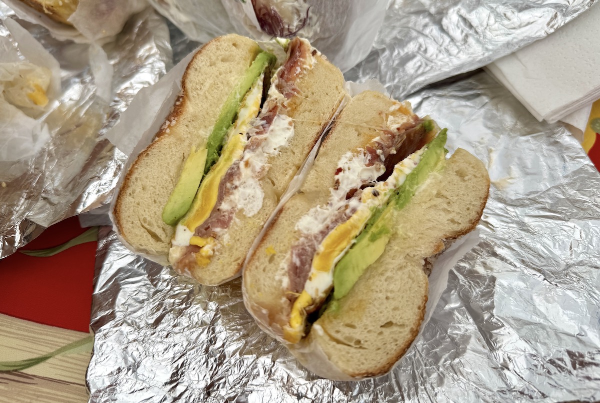 two halves of a stuffed bagel sandwich on foil