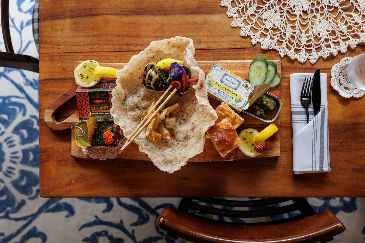 tinned fish and sides arrayed on wooden board