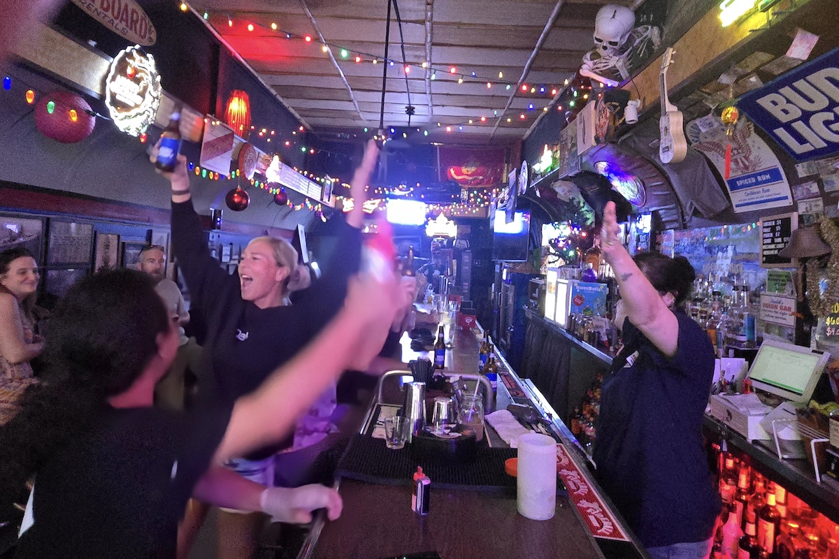 customers at smith’s union bar raise their bottles in a cheer