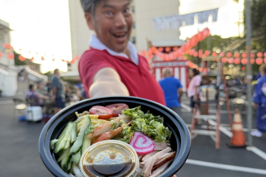 man holding bowl of noodles at bon dance