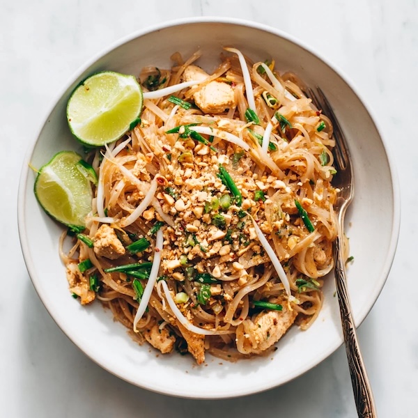 plate of pad thai noodles with lime wedges